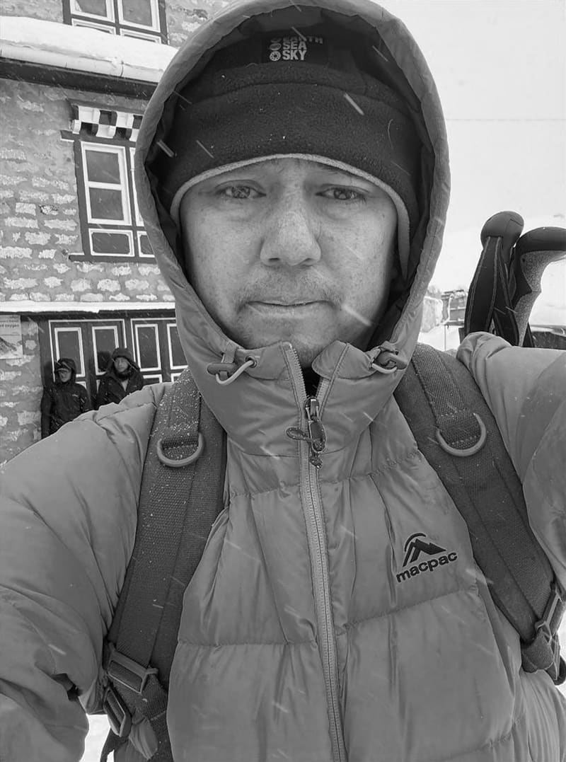 Black-and-white close-up of David in a hooded jacket, looking tired in the snow